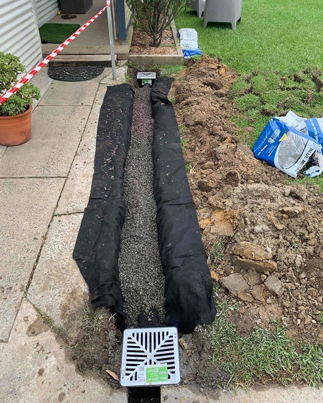 On Going Drainage Repair Beside A Grass Lawn — Bridge Plumbing & Trades in Nowra, NSW
