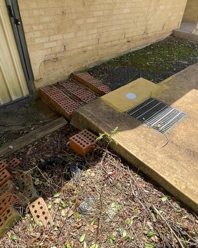 A Drainage On A Footpath With Few Blocks Beside — Bridge Plumbing & Trades in Berry, NSW