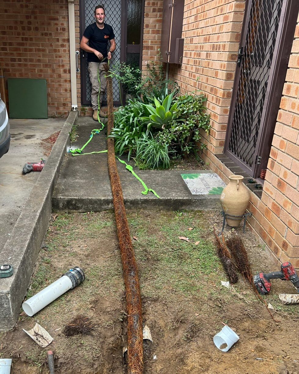 Man Stands Near an Open Trench With a Pipe — Bridge Plumbing & Trades In Gerringong, NSW