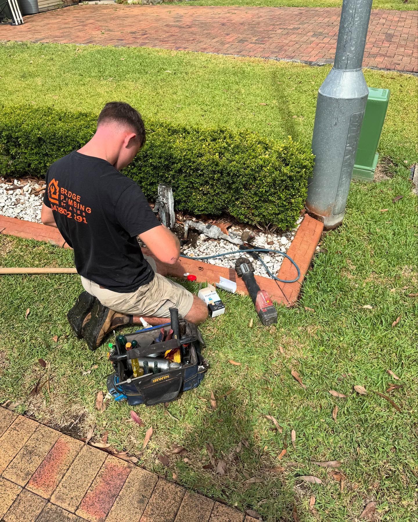 Man Working on Equipment Outdoors Next to a Pole — Bridge Plumbing & Trades In Shellharbour, NSW