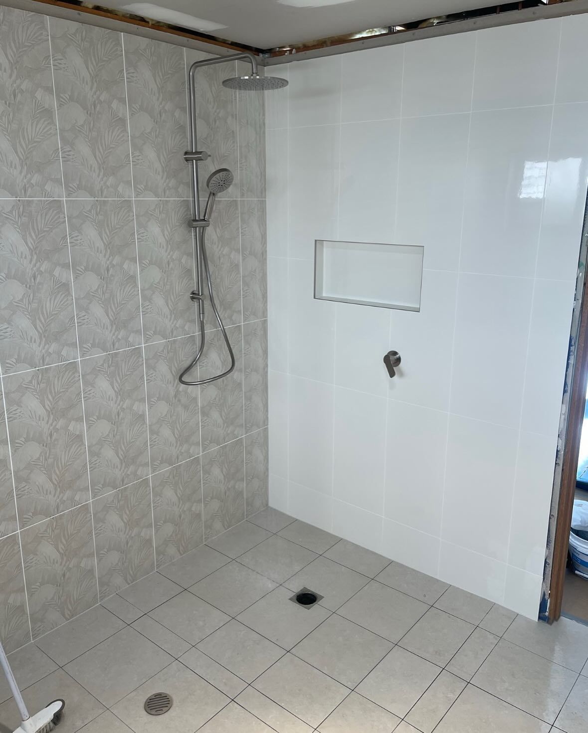 A Bathroom With White Tiles and a Shower Head — Bridge Plumbing & Trades in Nowra, NSW