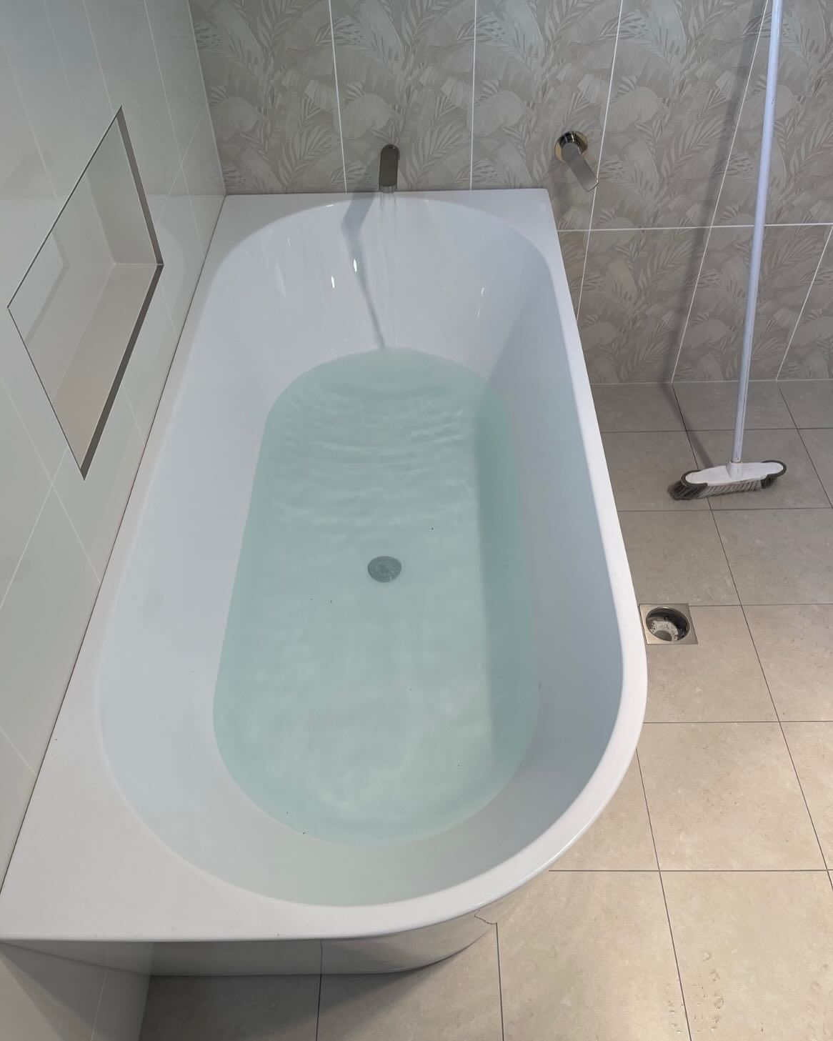 A Bathtub Filled With Blue Water in a Bathroom — Bridge Plumbing & Trades in Nowra, NSW
