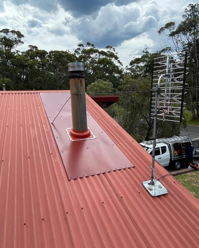Red House Roof With A Chimney And Trees In Background — Bridge Plumbing & Trades in Nowra, NSW