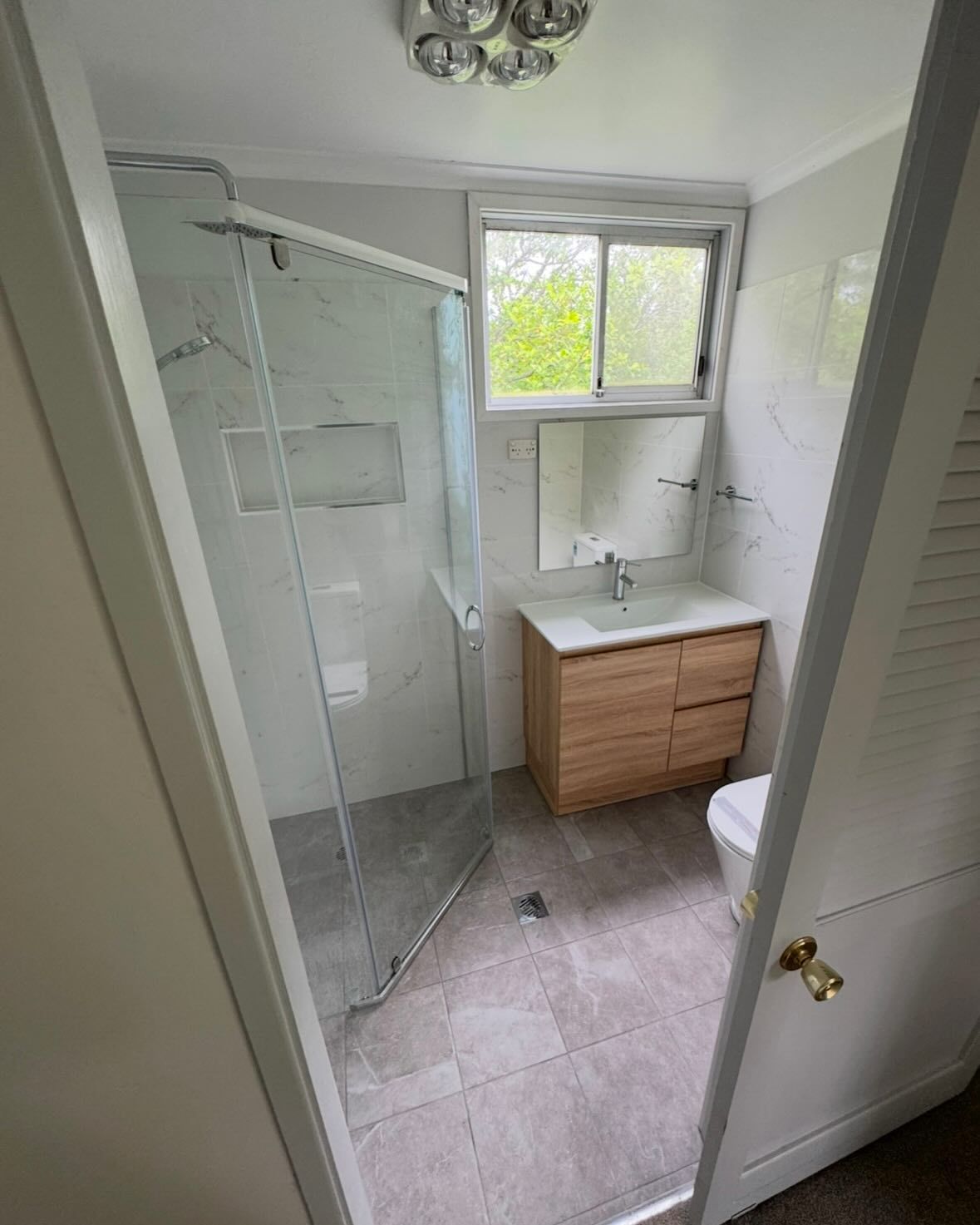 Bathroom With A Glass Shower, Vanity Mirror, And Toilet