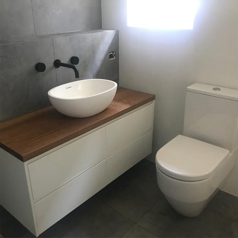 A Bathroom With A Sink, A Black Tap And A Toilet Seat — Bridge Plumbing & Trades in Nowra, NSW