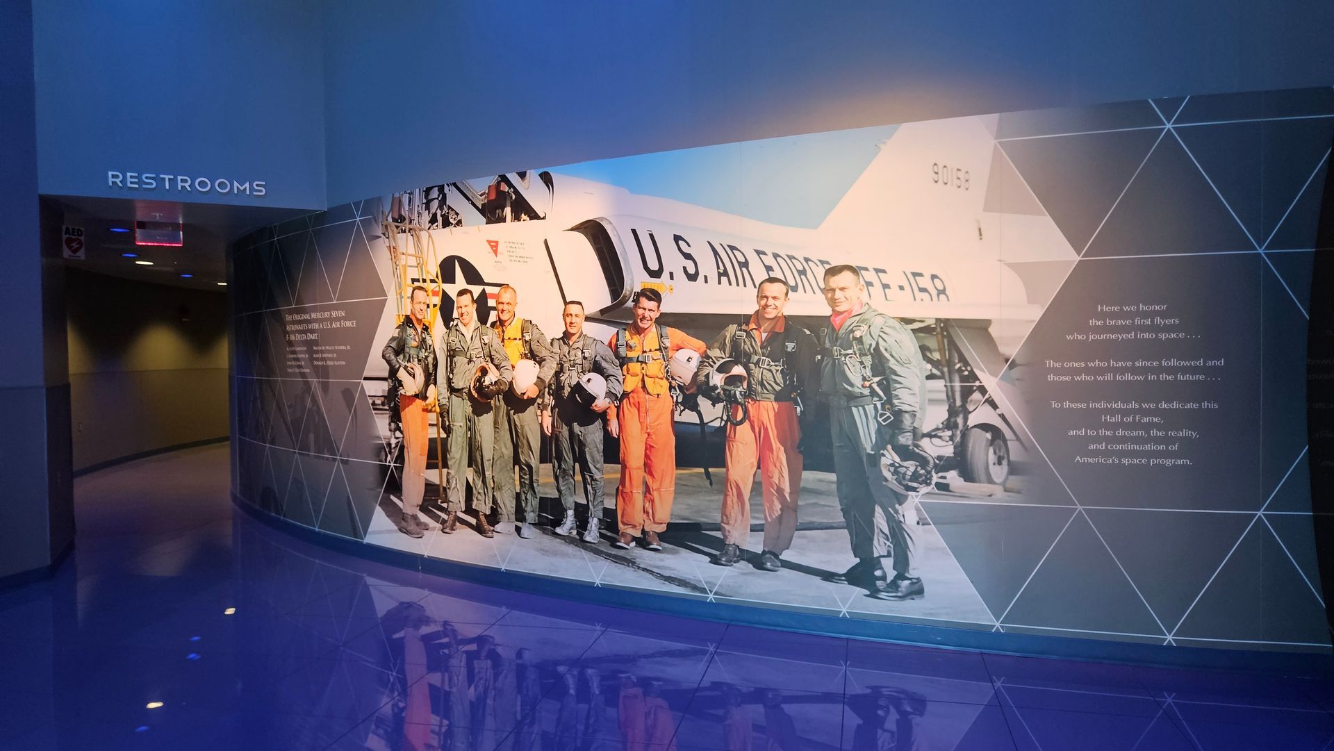 Wall display: historic photo of U.S. Air Force pilots, text, geometric shapes, in a museum with blue floor.