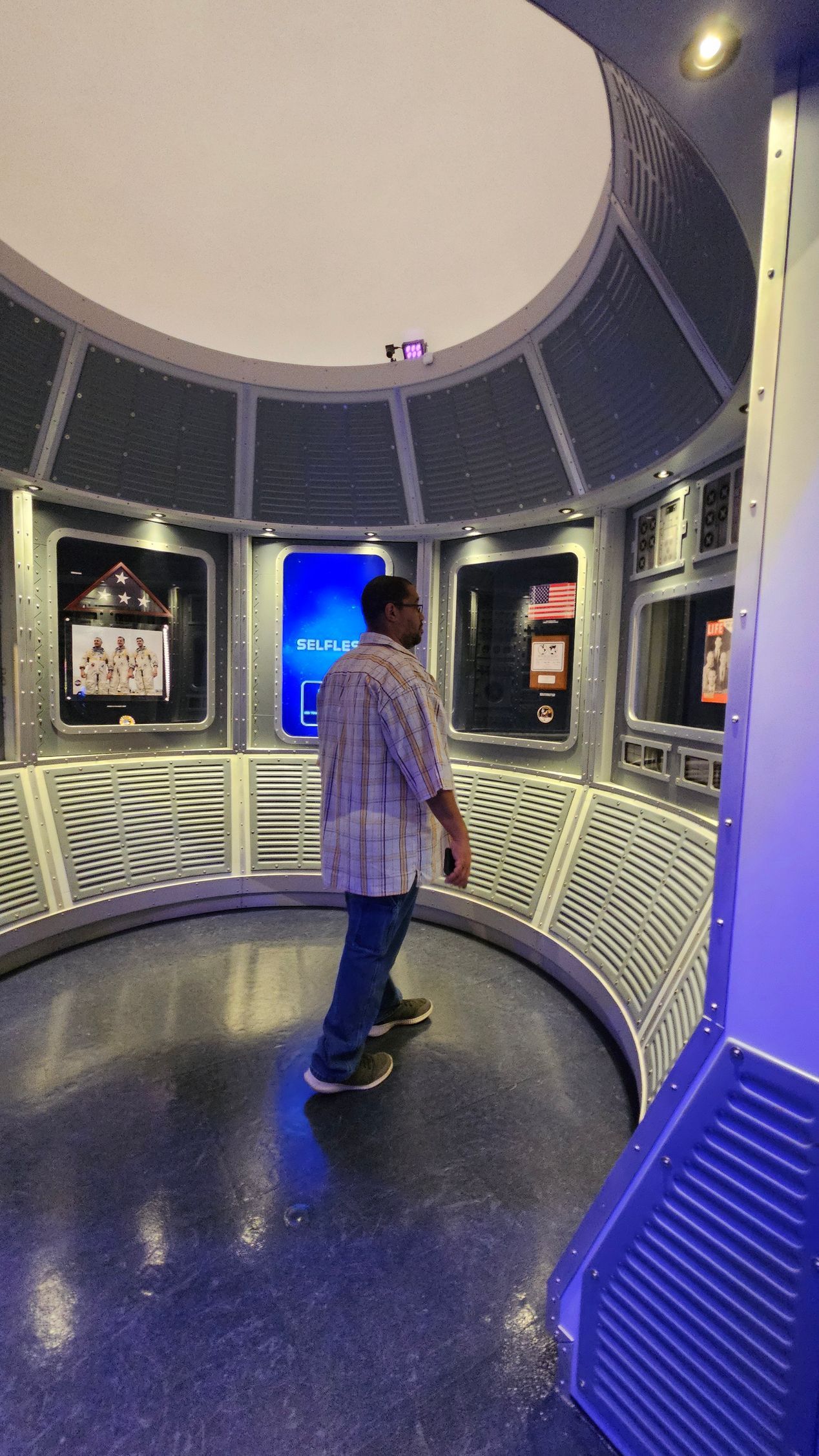 Man stands in a circular room with displays, possibly a museum or exhibit.