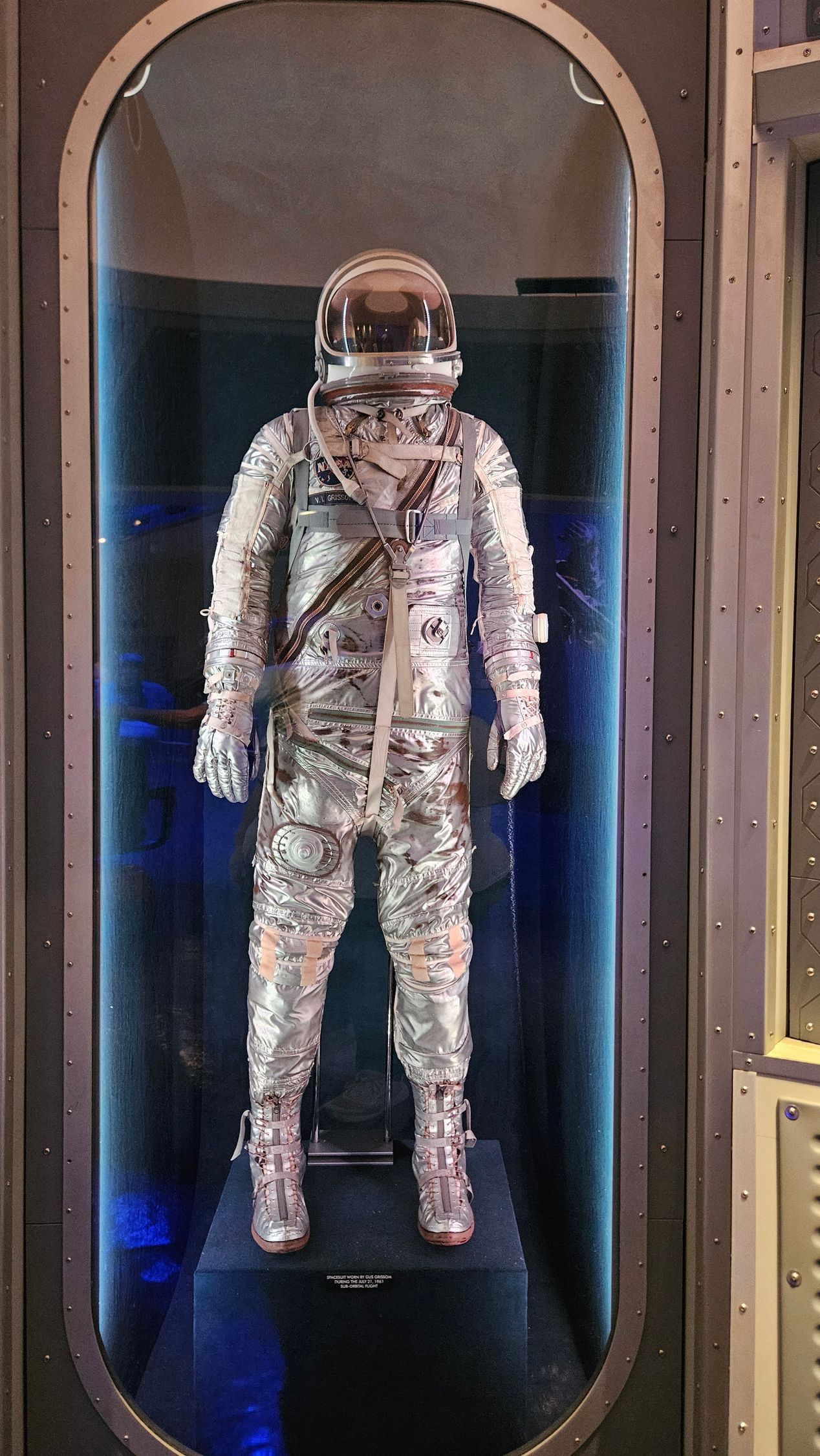 Astronaut suit in a glass display case with blue lighting.