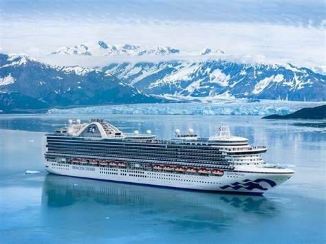 Cruise ship sailing through icy blue waters with snowy mountains in the background