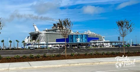 Large white cruise ship docked at a port under a bright blue sky
