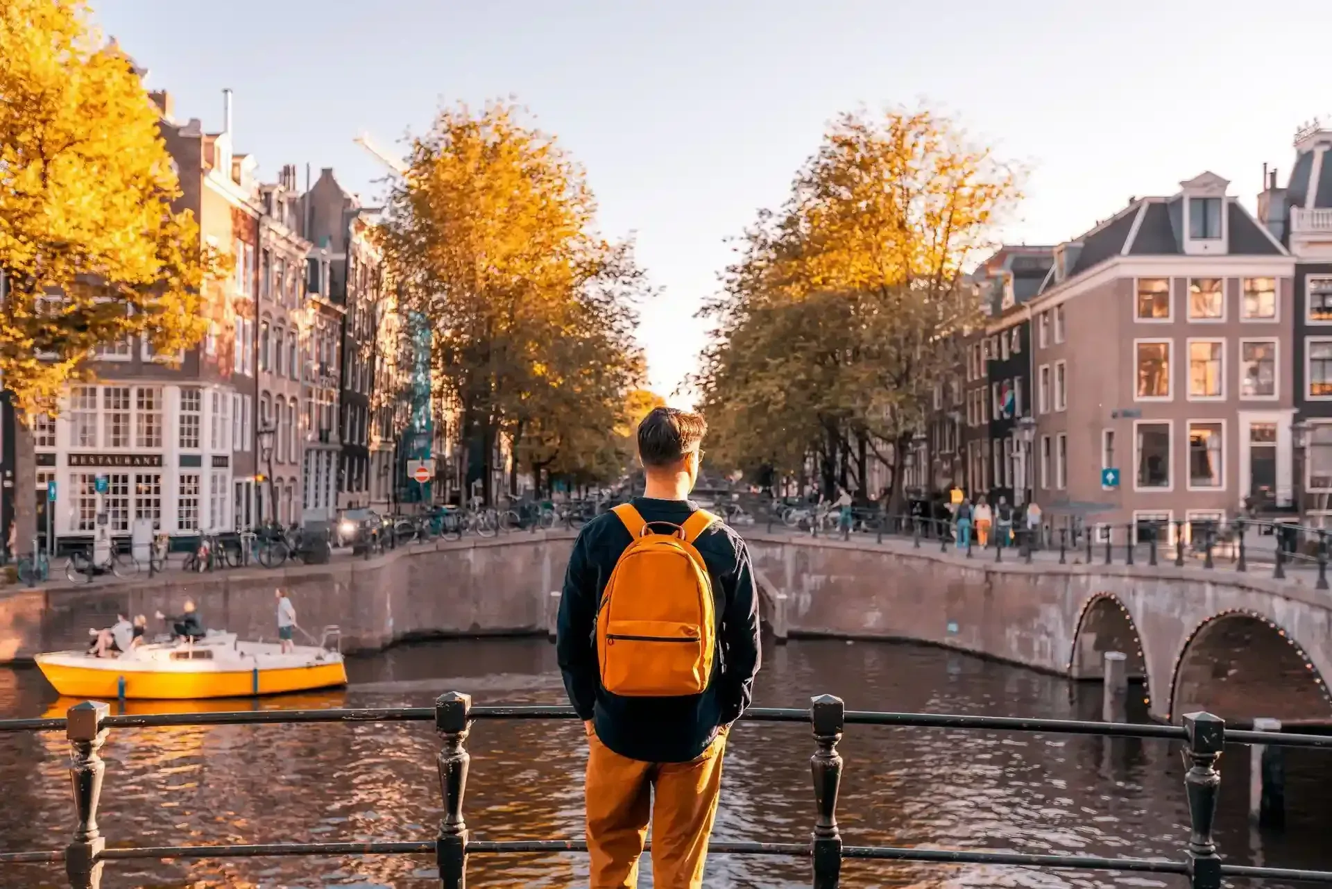 A man with a backpack is standing on a bridge over a river.