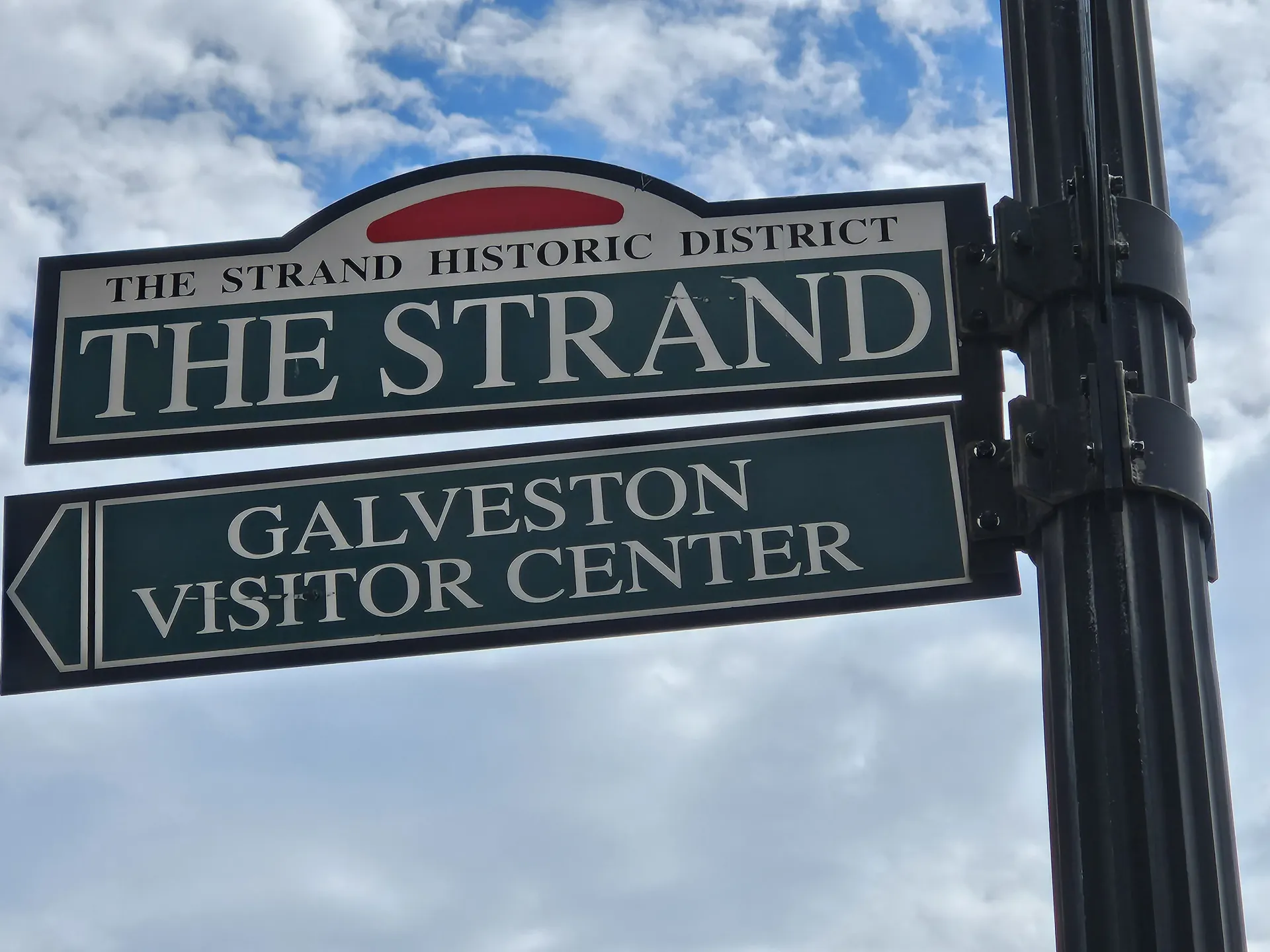 A street sign for the strand and galveston visitor center