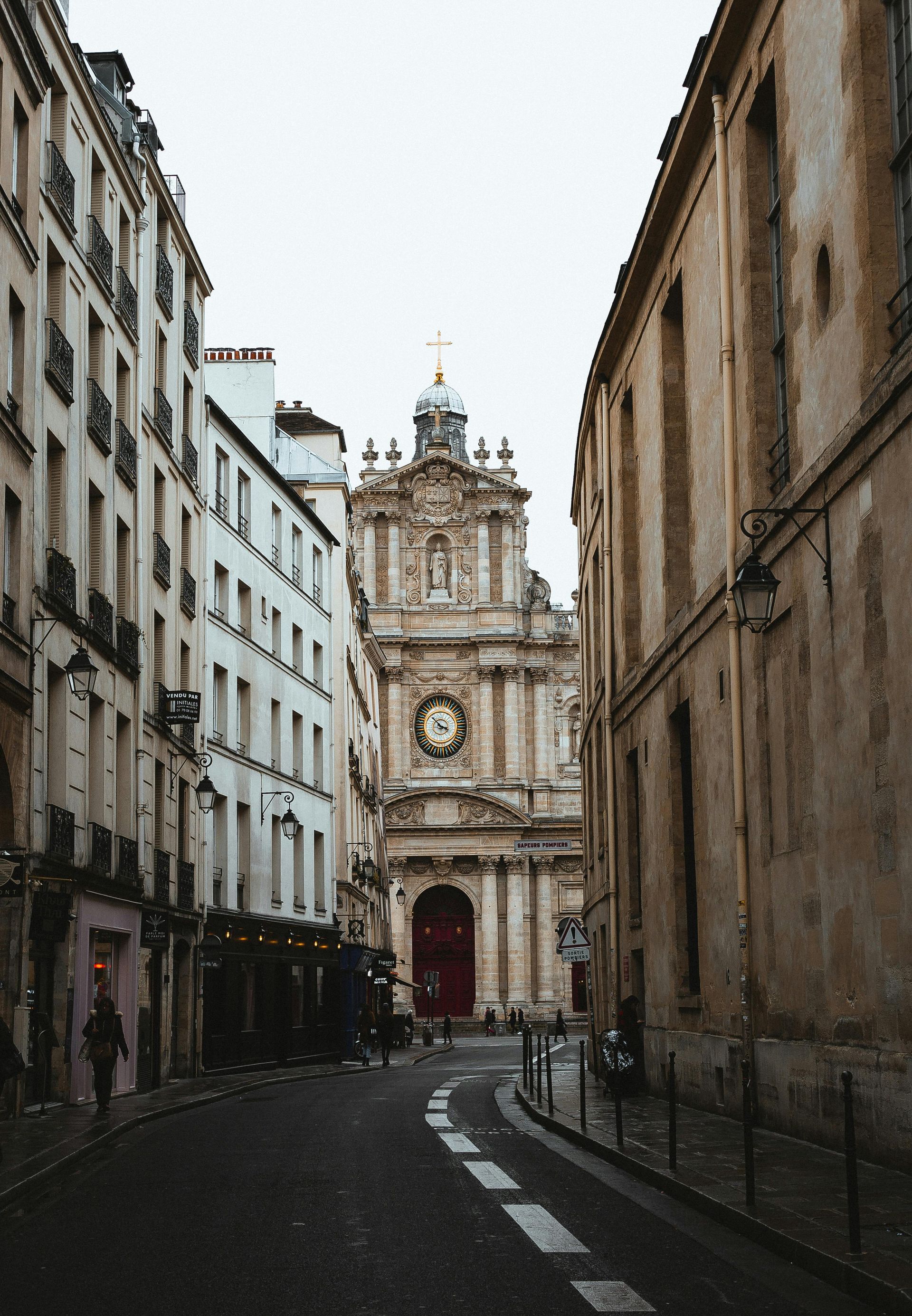 A narrow street with a clock tower in the middle of it