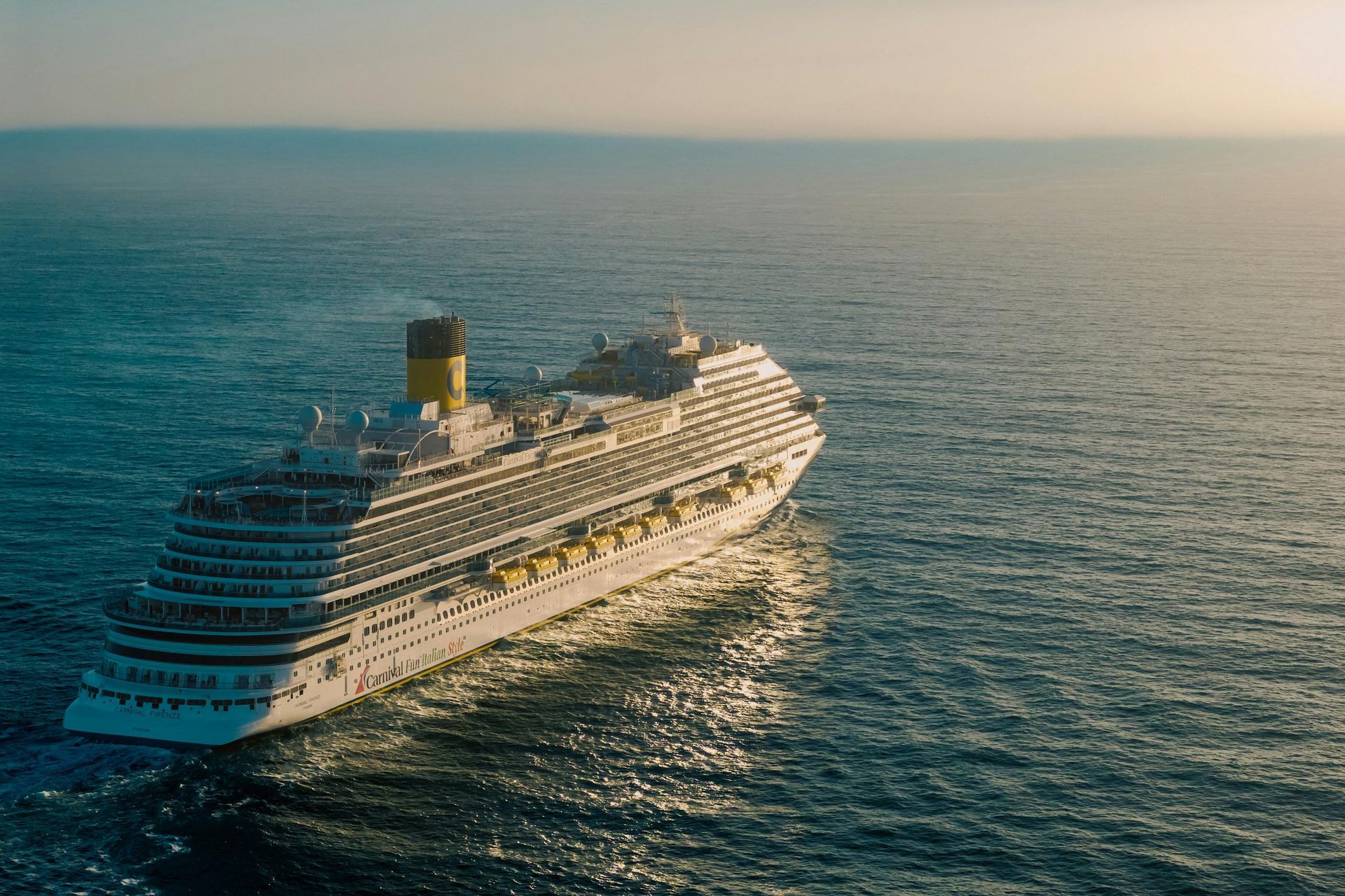 Large white cruise ship sailing on calm blue ocean at sunset