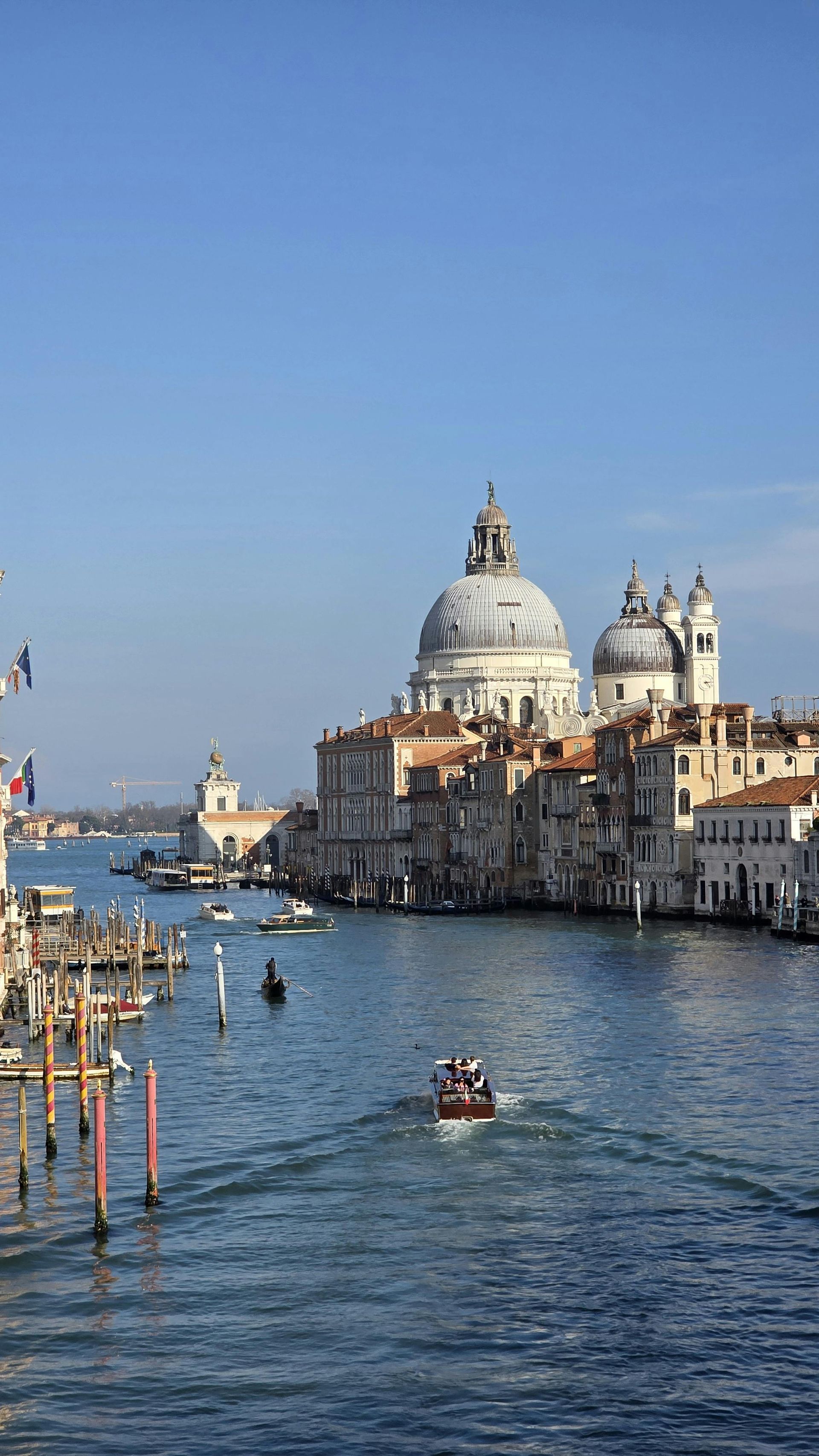 Venice canal with gondolas and the domed Santa Maria della Salute church under a clear blue sky