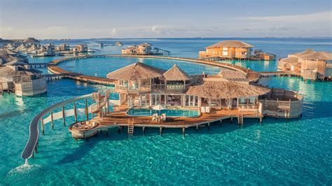 Overwater resort villas on turquoise sea connected by wooden walkways