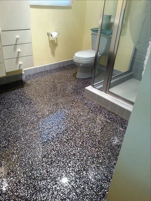 A bathroom with a dark, multi-colored speckled epoxy floor.