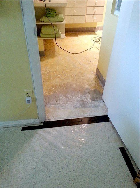 A threshold transitions from a speckled light floor to a darker room.