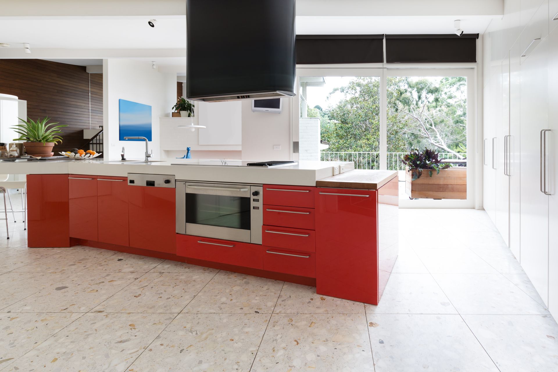 A modern kitchen featuring a bright red island with a built-in oven.