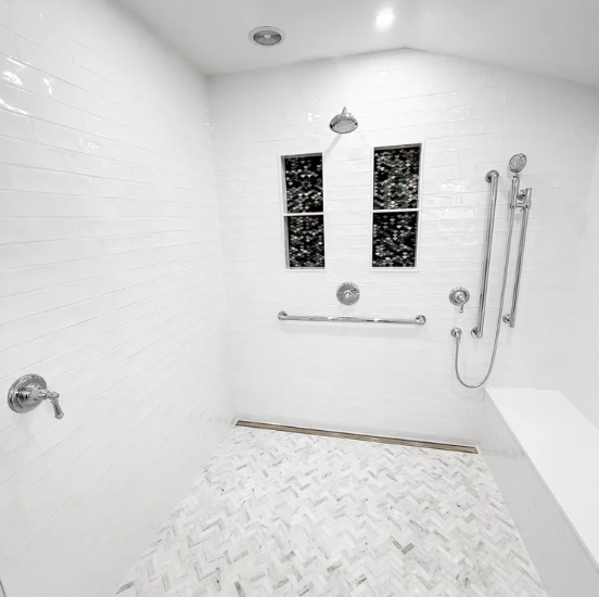 Bright white walk-in shower with bench, grab bars, handheld sprayer, and tiled floor.
