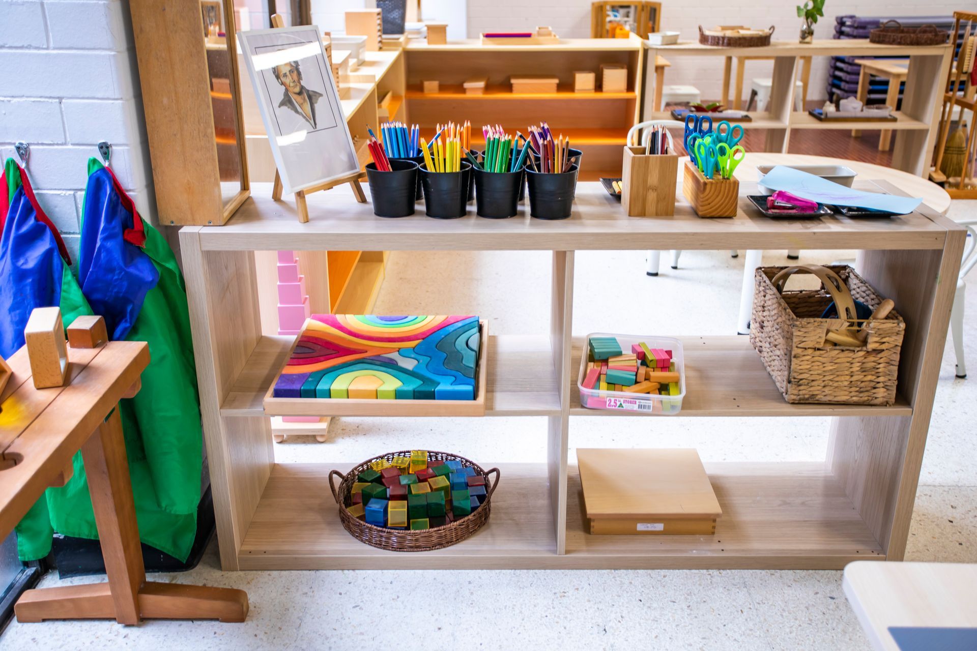 A wooden shelf filled with toys and pencils in a classroom.