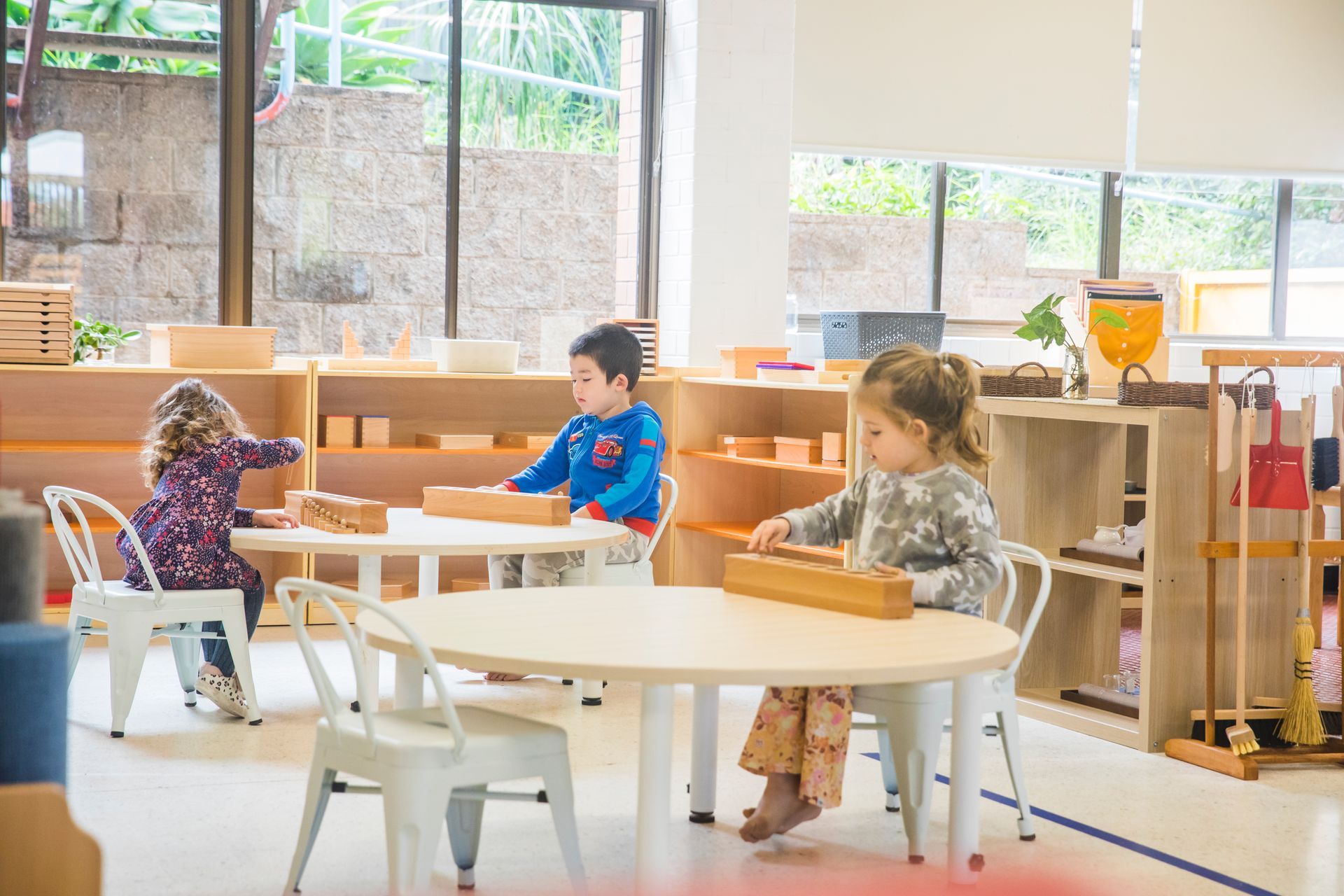 A group of children are sitting at tables in a classroom playing with toys.