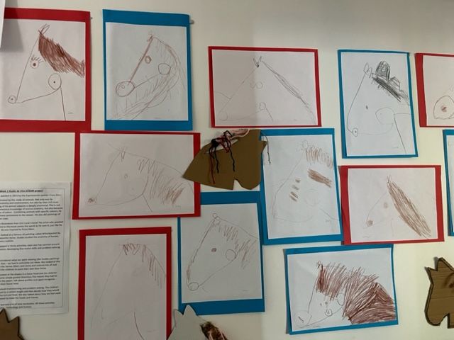 Children 's drawings of horses are displayed on a wall