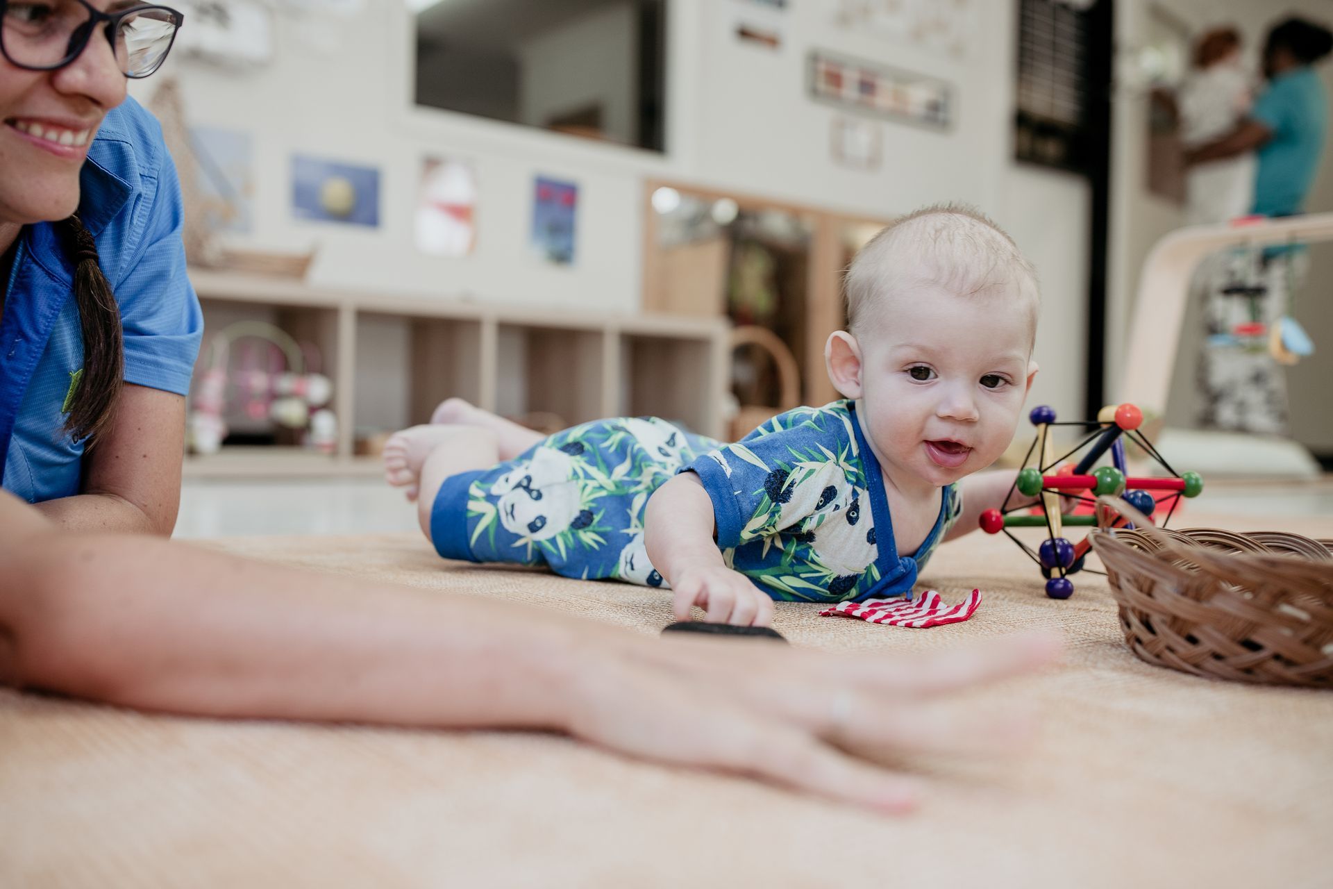 A woman is playing with a baby on the floor.
Montessori-based play.