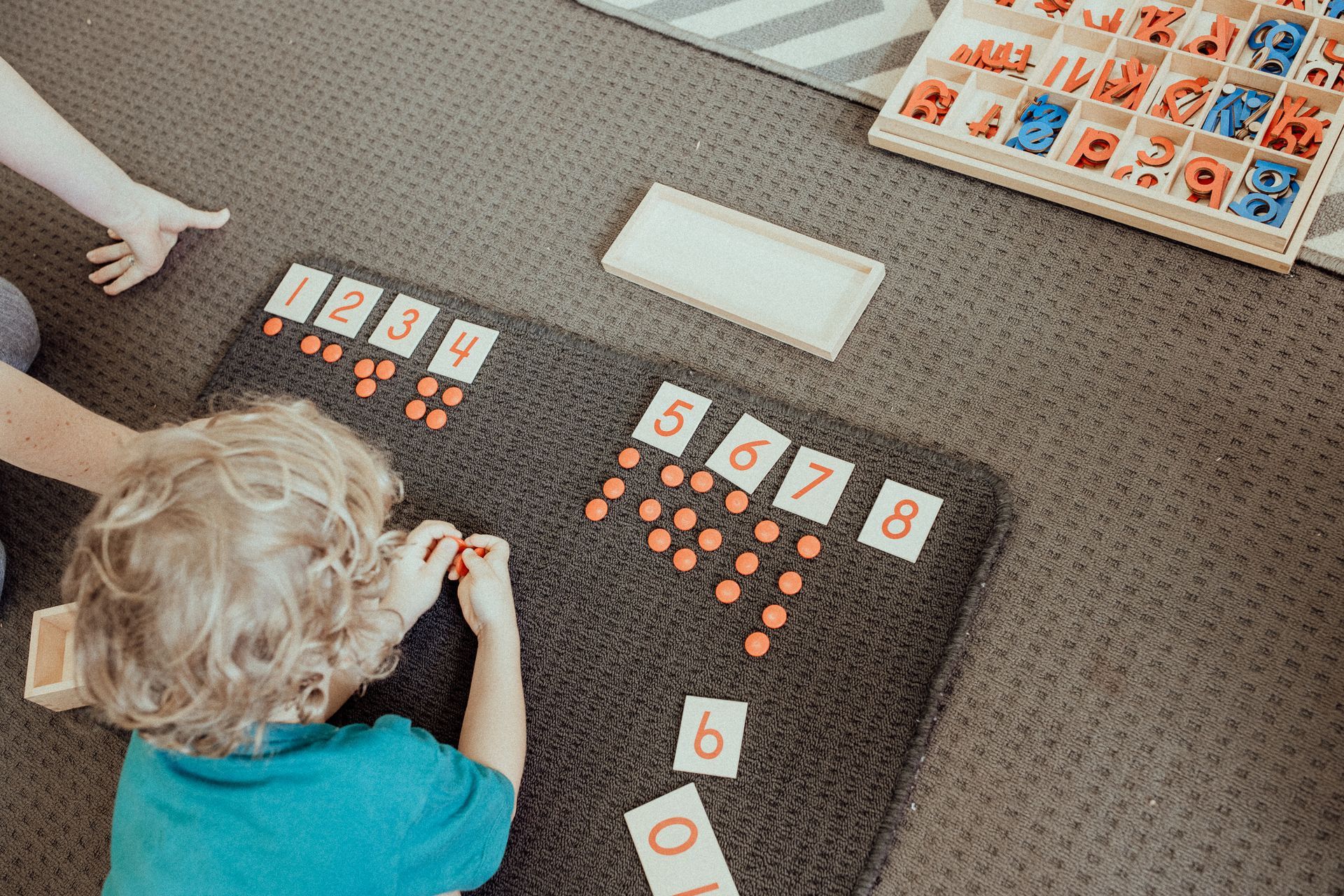 A young boy is playing with numbers on a mat on the floor.