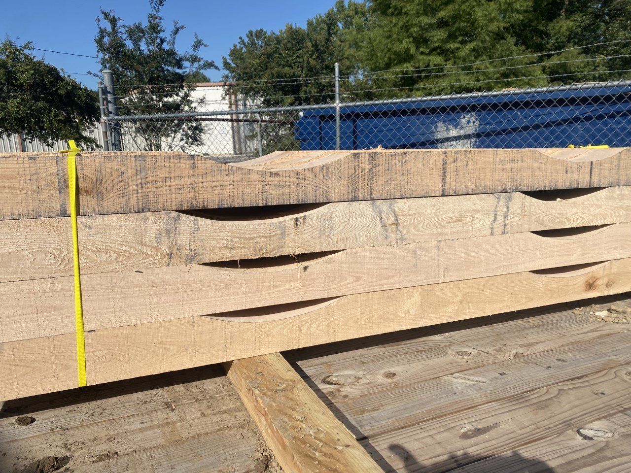 A yellow tape measure is sitting on top of a pile of wood.