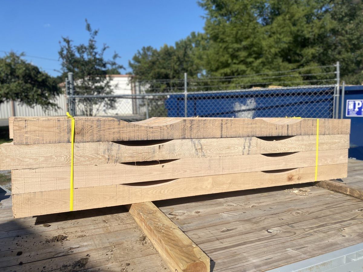 A stack of wood is tied together with a yellow strap