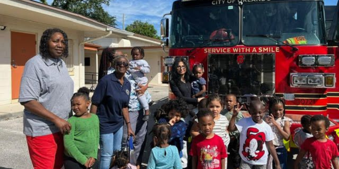A group of children are standing in front of a fire truck.
