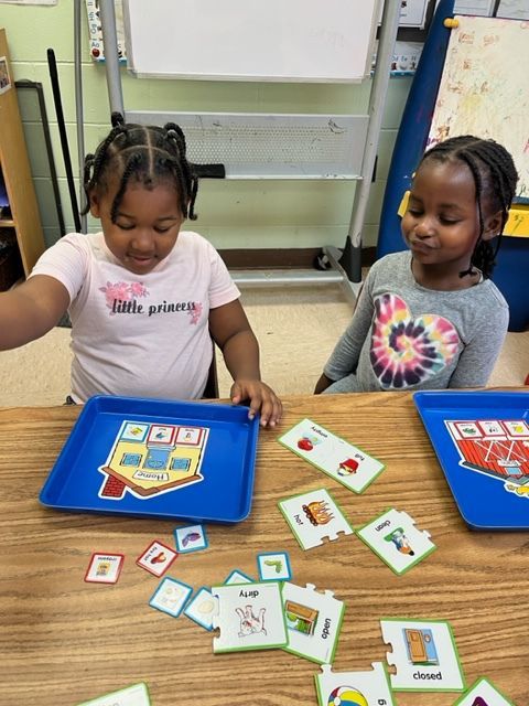 Two little girls are sitting at a table playing a game