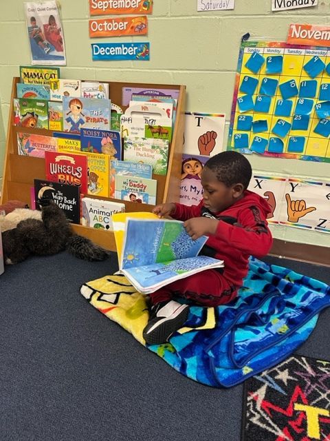 A young boy is sitting on the floor reading a book