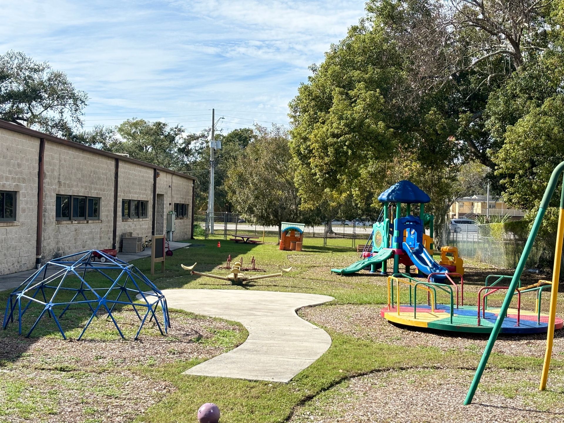 A playground with a slide and swings in front of a building.