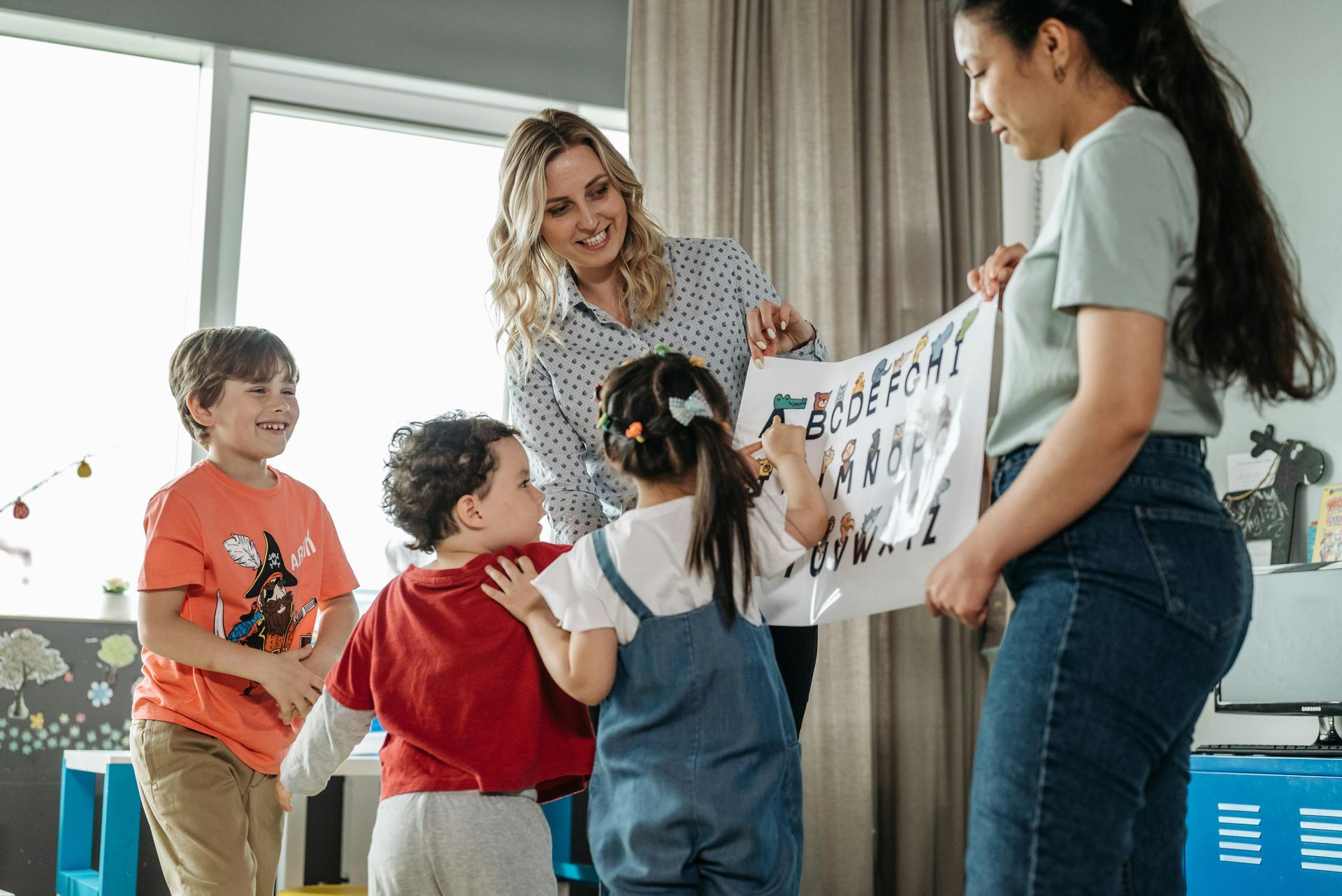 A group of children are standing around a woman holding a piece of paper.