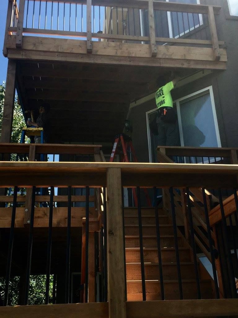Covered outdoor patio with a concrete floor, stone columns, and wood beams.