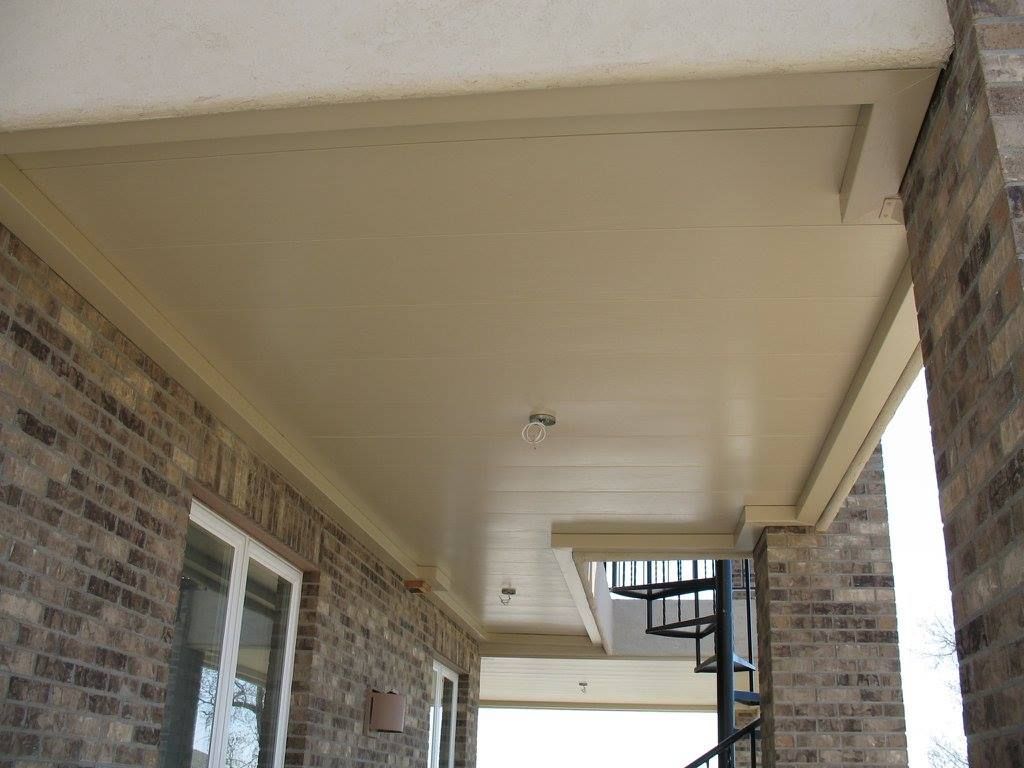 Outdoor patio with red sofa, stone fireplace, and dark ceiling.