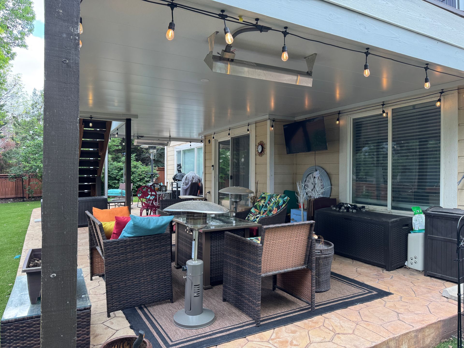 Covered patio with seating area, string lights, and a heater.