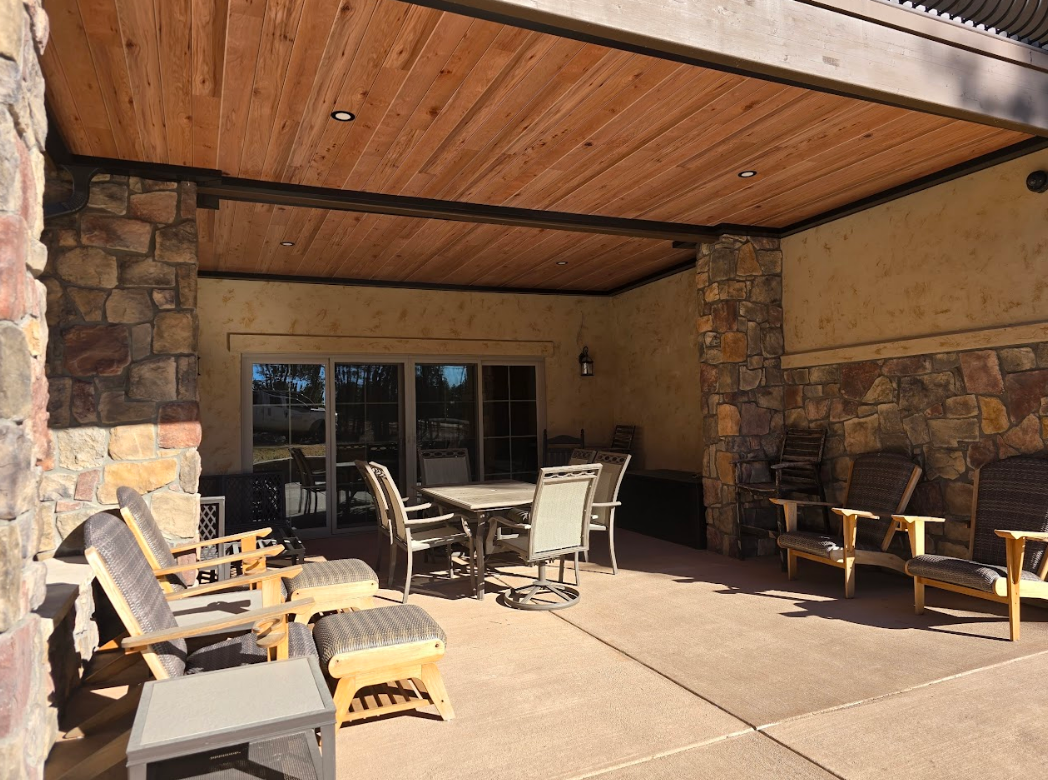 Patio with stone columns, wood ceiling, and outdoor furniture.