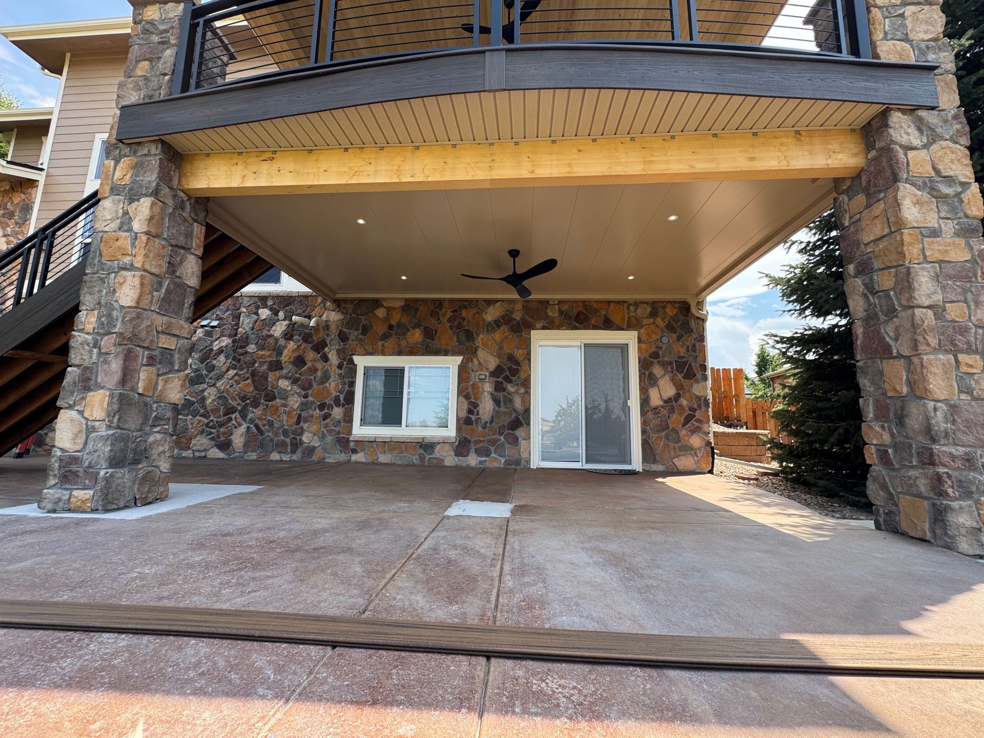 Outdoor walkway under a dark gray roof. Light-colored walls and gray pavers.
