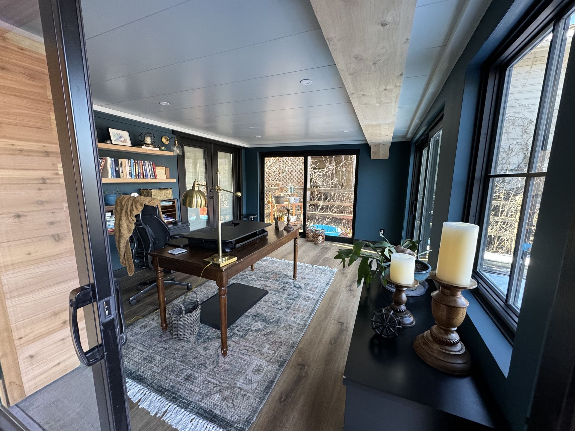 Two-story house with deck, brown and tan exterior, black railing. Sunny day.