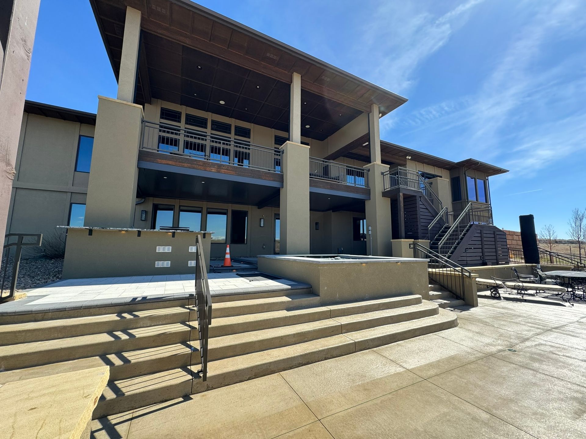 Covered patio with white underside and brown support posts, next to a building and fence.