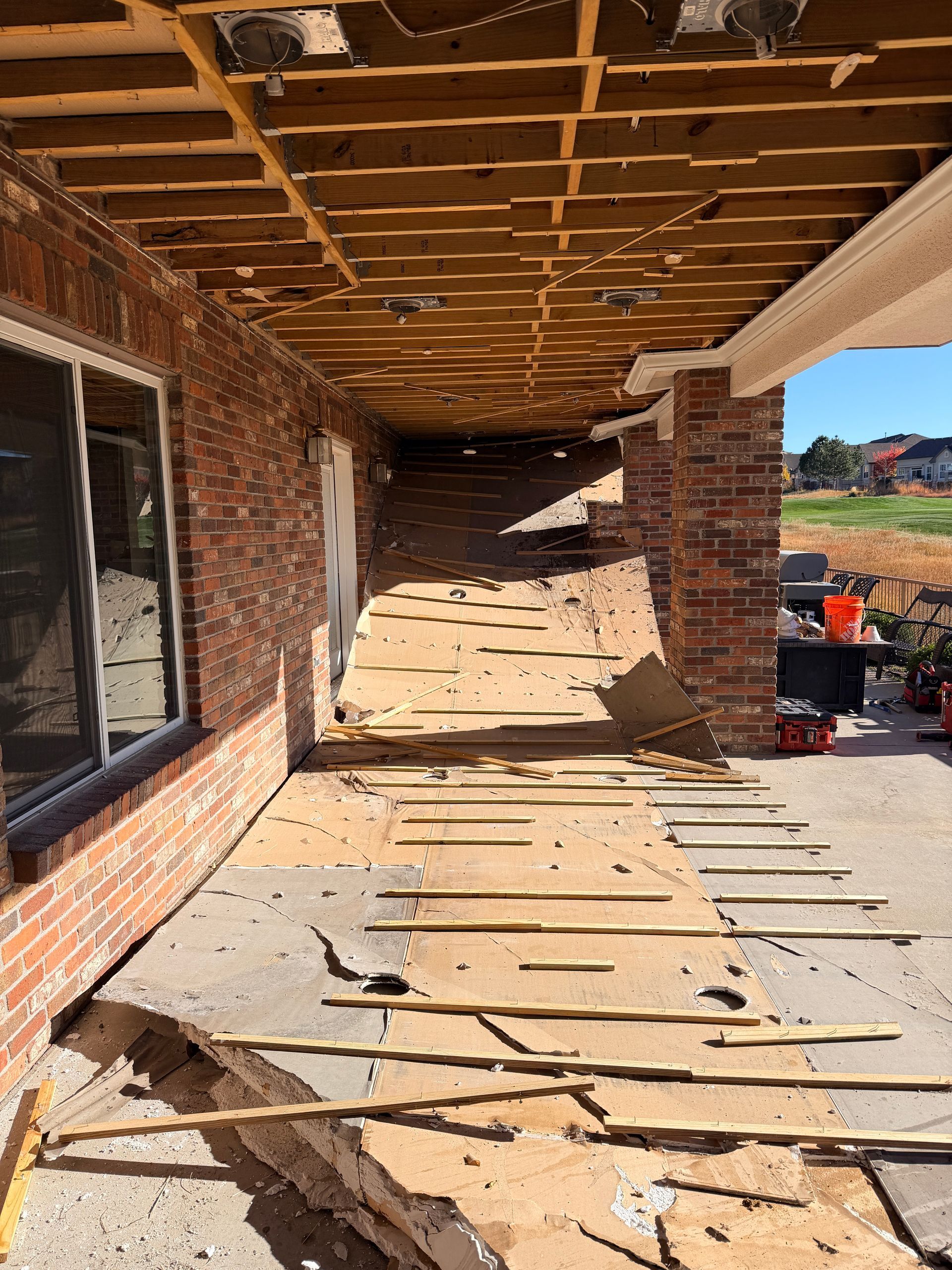 Covered outdoor patio with a concrete floor, stone columns, and wood beams.