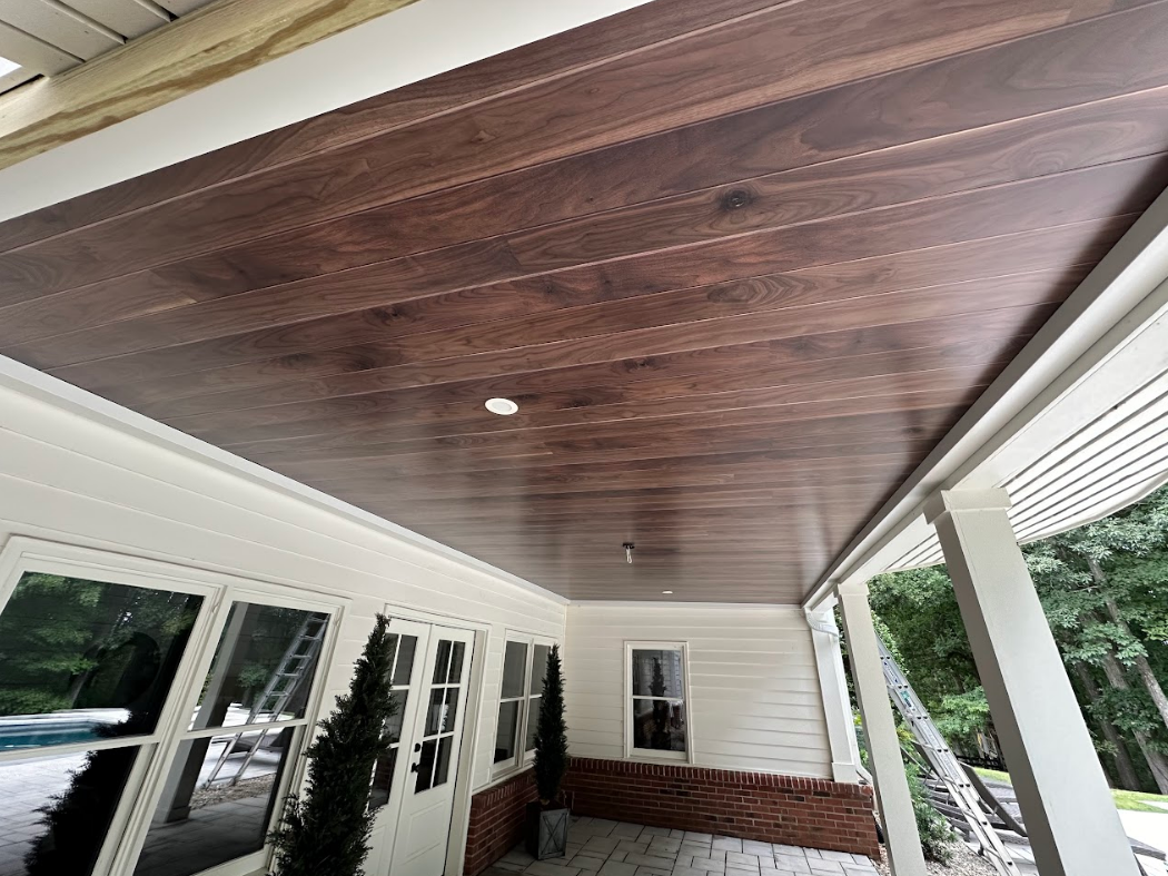 Brown wooden porch ceiling with white trim and a single light fixture.
