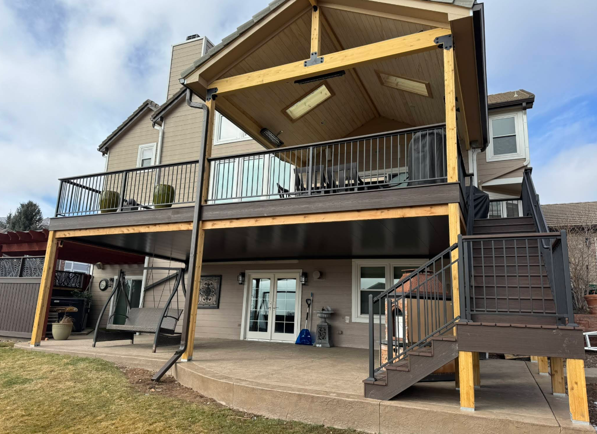 Ceiling fan with five blades, mounted on a gray, slatted ceiling.  String lights are visible.
