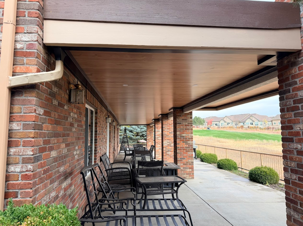 Outdoor patio with red sofa, stone fireplace, and dark ceiling.