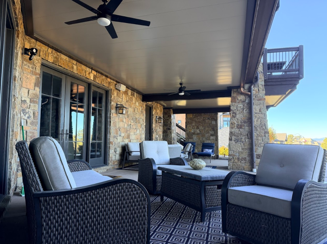 Outdoor patio with red sofa, stone fireplace, and dark ceiling.