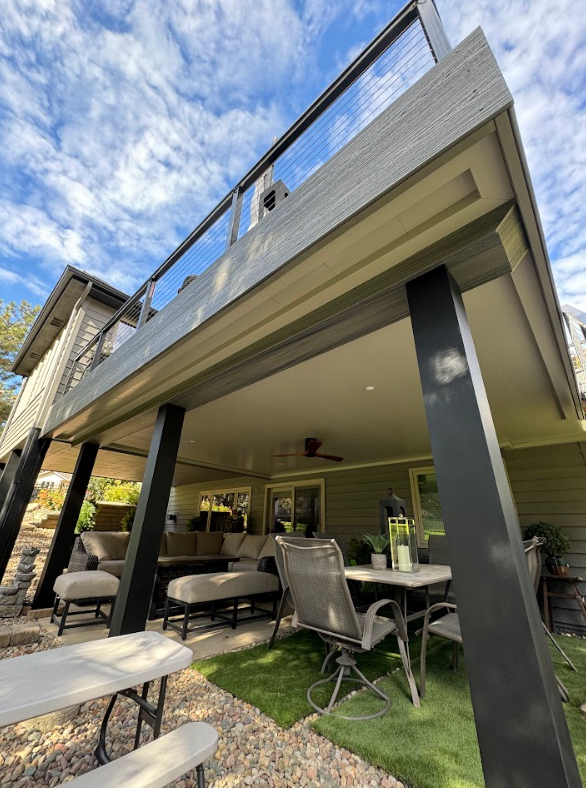 Outdoor deck with black supports and seating area underneath.
