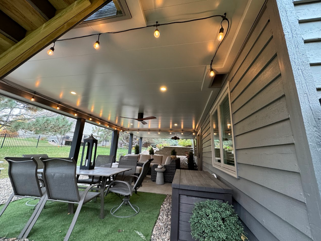Outdoor patio with string lights, seating, and a grey ceiling.